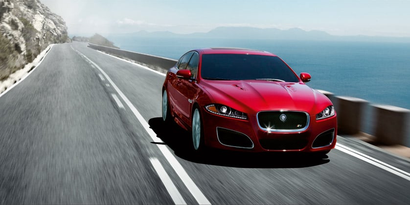 Kırmızı XFR sedan sahil yolunda önden
