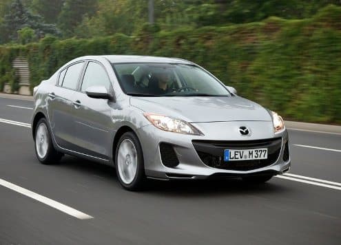 Gümüş Mazda3 sedan yolda ön üç çeyrek görünümü