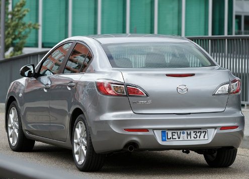 Gümüş Mazda3 sedan şehir ortamında arka görünüm