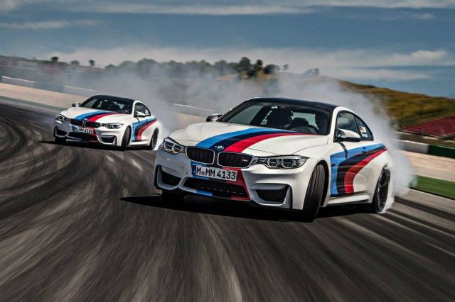 İki beyaz BMW M4 Coupe dumanlı pistte