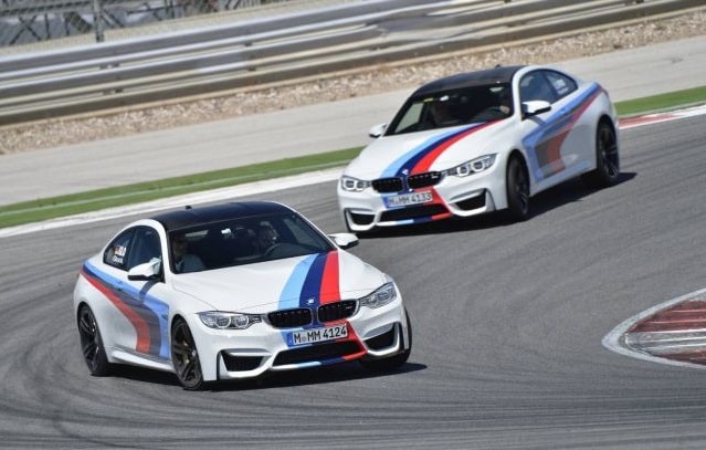 Pistte art arda ilerleyen iki beyaz BMW M4 Coupe