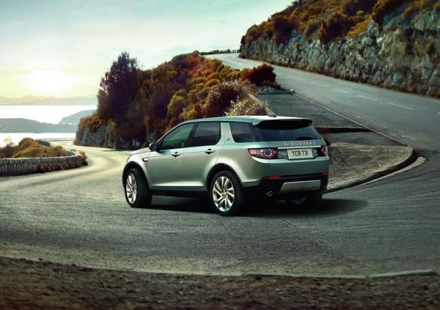 Gümüş Land Rover Discovery Sport virajda arkadan görünüm