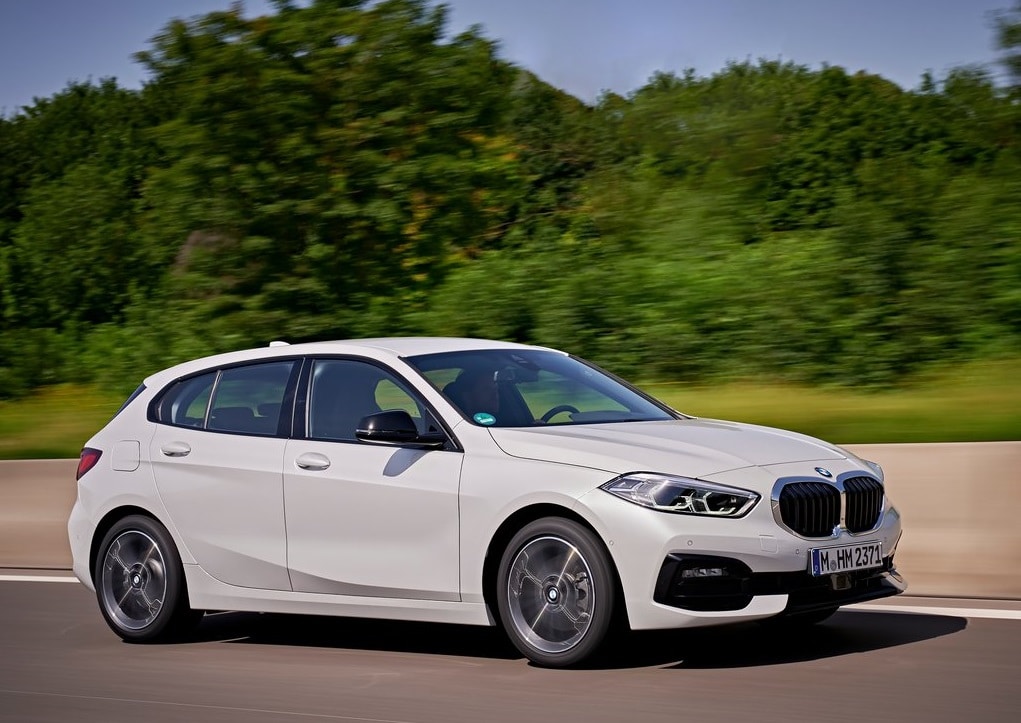 Beyaz BMW 1 Serisi yolda hareket halinde ön gövde görünümü