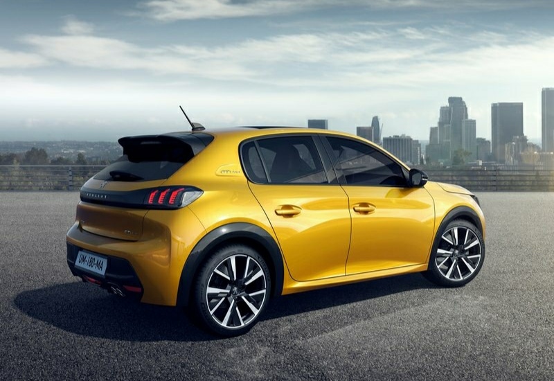 Şehir manzarası önünde duran sarı Peugeot 208