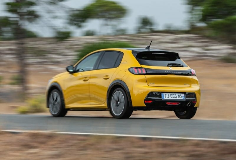 Yolda ilerleyen sarı Peugeot 208 arka ve yan görünümü