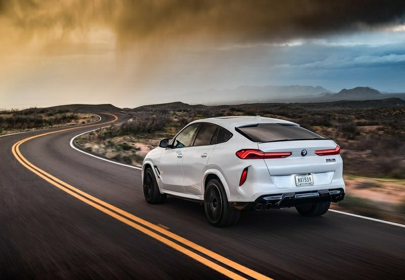 Beyaz BMW X6 M Competition yolda arka görünümü