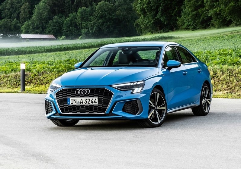 Mavi Audi A3 Sedan yeşil alan önünde ön ve yan gövde görünümü