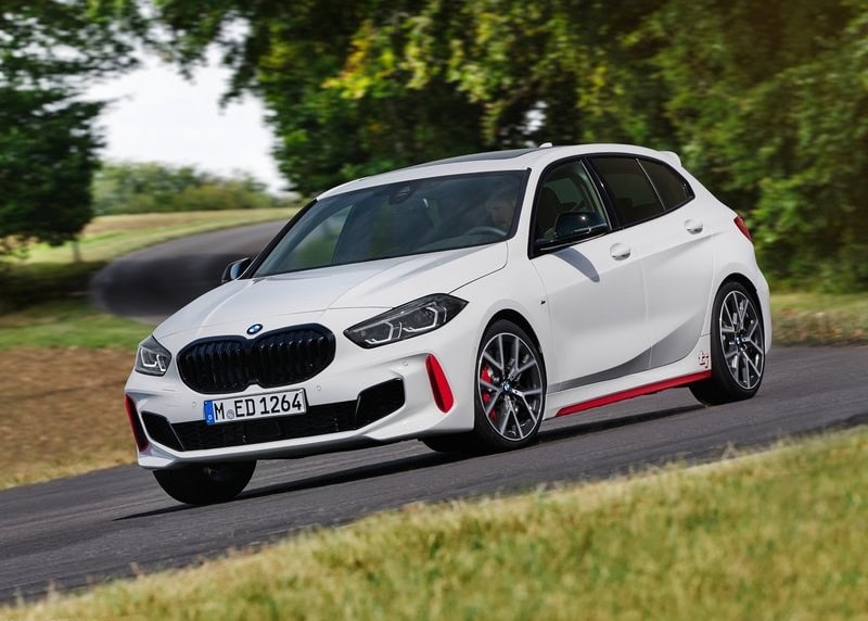 Beyaz BMW 128ti yolda hareket halinde ön ve yan görünüm