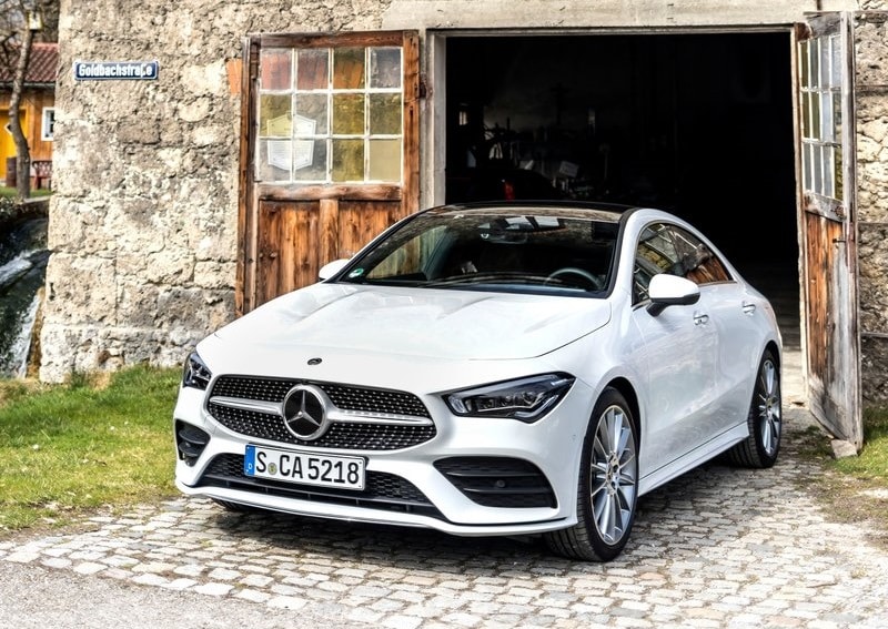 Beyaz Mercedes-Benz CLA taş yapının önünde park halinde