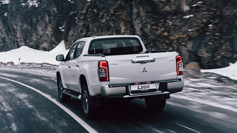 Beyaz Mitsubishi L200 karlı yolda arka gövde görünümü