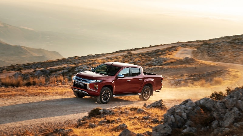 Kırmızı Mitsubishi L200 toprak yolda sürüş halinde