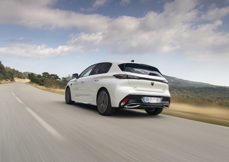 Beyaz Peugeot 308 yol üzerinde hareket halindeyken arka yan görünümü