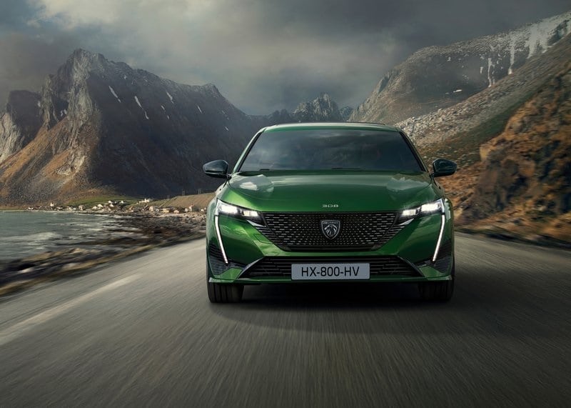 Yeşil Peugeot 308 dağ yolunda önden hareket görünümü