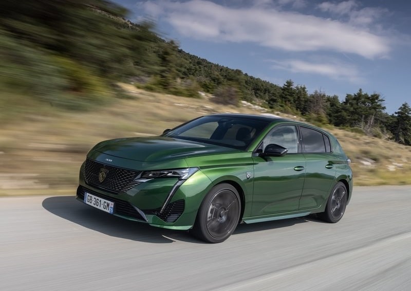Yeşil Peugeot 308 yol üzerinde hareket halindeyken ön yan görünümü