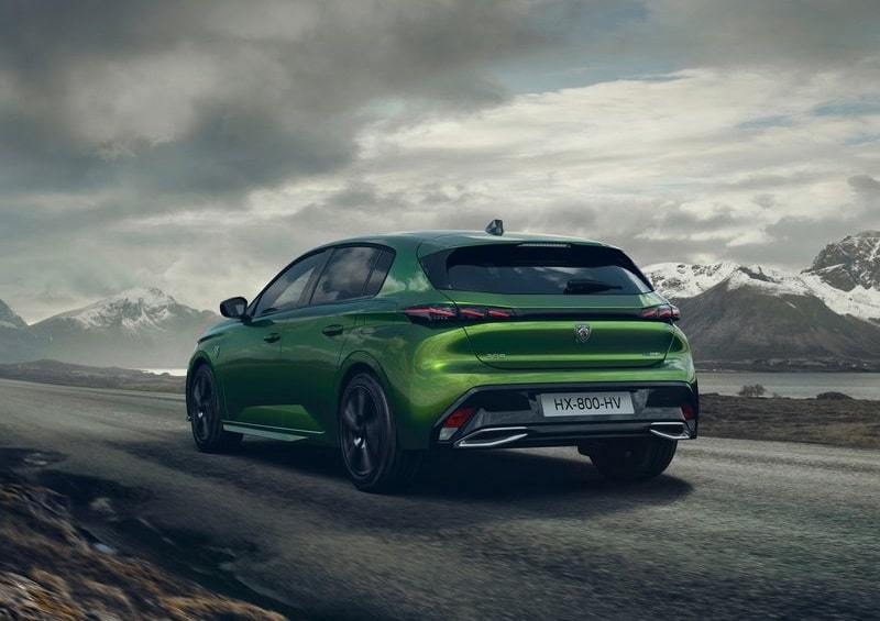 Yeşil Peugeot 308 dağ yolunda hareket halindeyken arka yan görünümü
