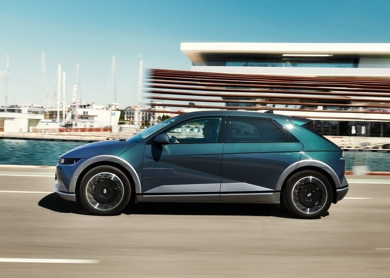 Mavi IONIQ 5 sahil yolunda hareket halinde yan profil