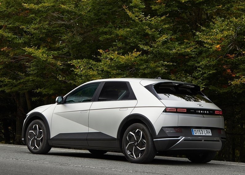 Beyaz IONIQ 5 ağaçlık alanda arka üç çeyrek görünüm
