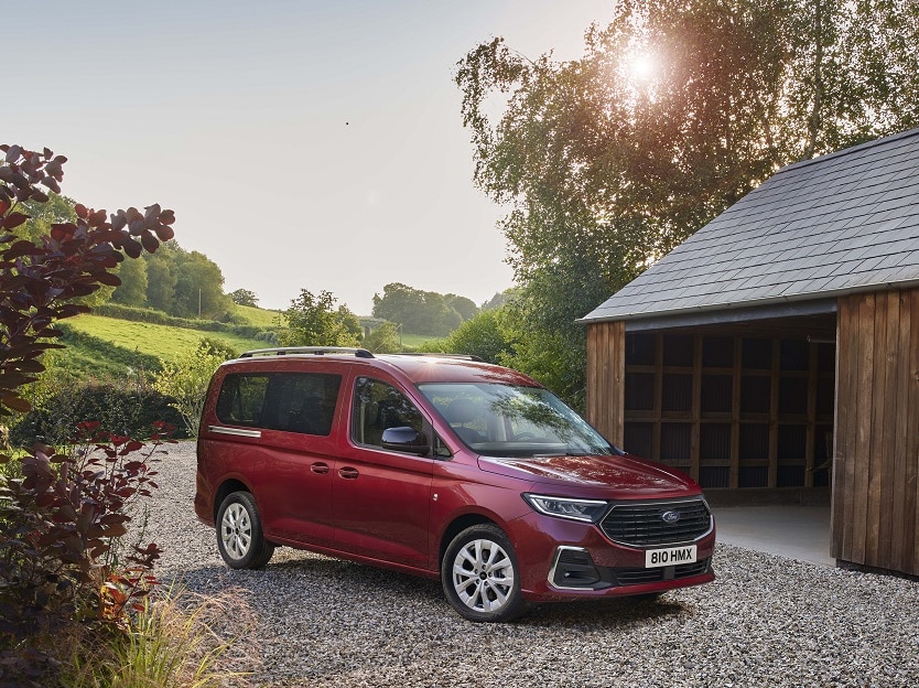 Kırmızı Ford Tourneo Connect ahşap yapı yanında park halinde
