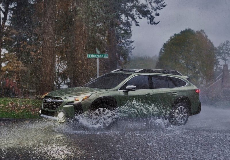 Subaru Outback yağmurlu yolda yan görünüm