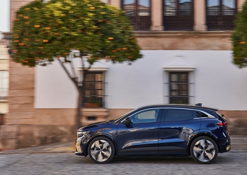 Lacivert Renault Megane E-Tech şehir içinde hareket halinde yan görünüm