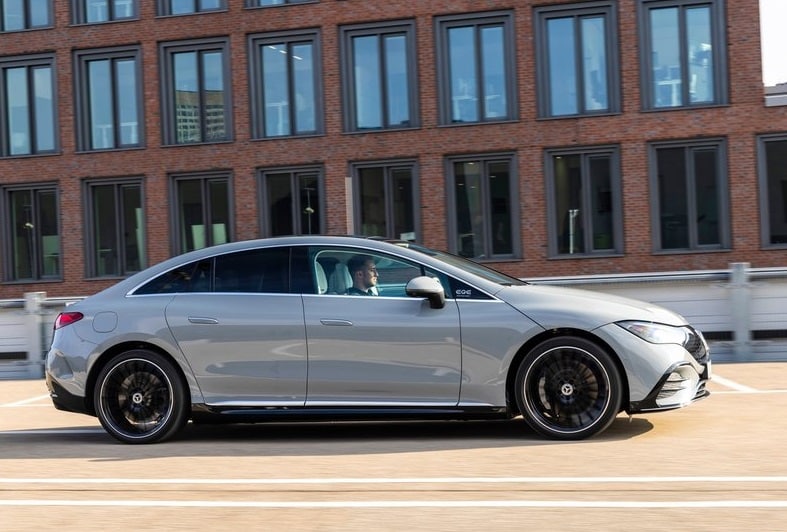 Gümüş renkli Mercedes-Benz EQE sedanın şehir yolunda yan profili