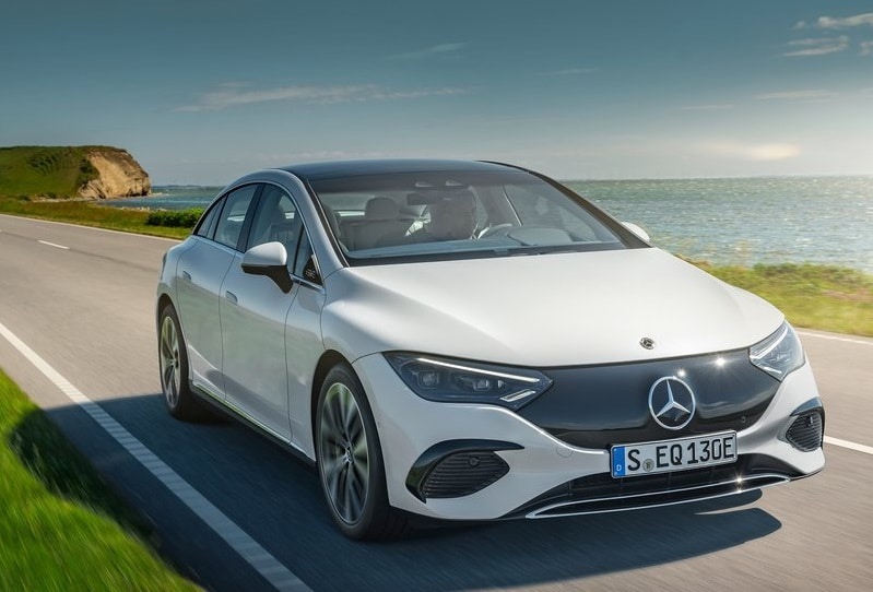 Beyaz Mercedes-Benz EQE sedanın sahil yolunda önden üç çeyrek görünümü