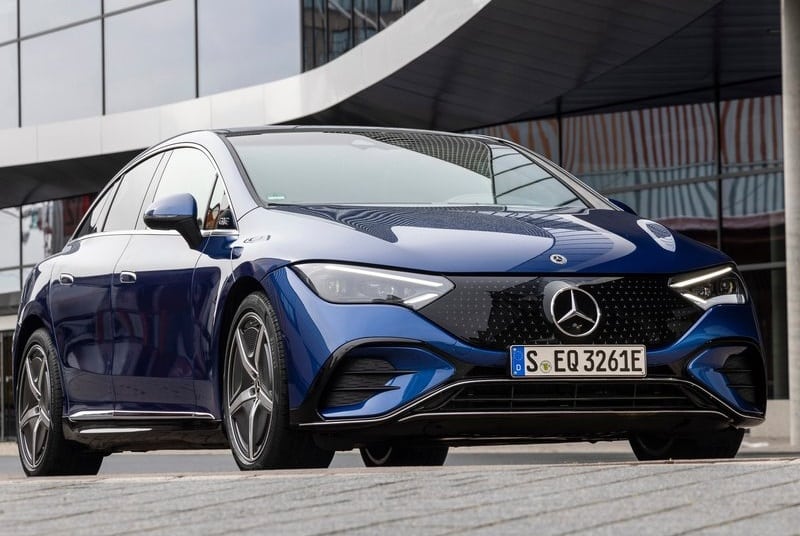 Mavi Mercedes-Benz EQE sedanın bina önünde önden üç çeyrek görünümü