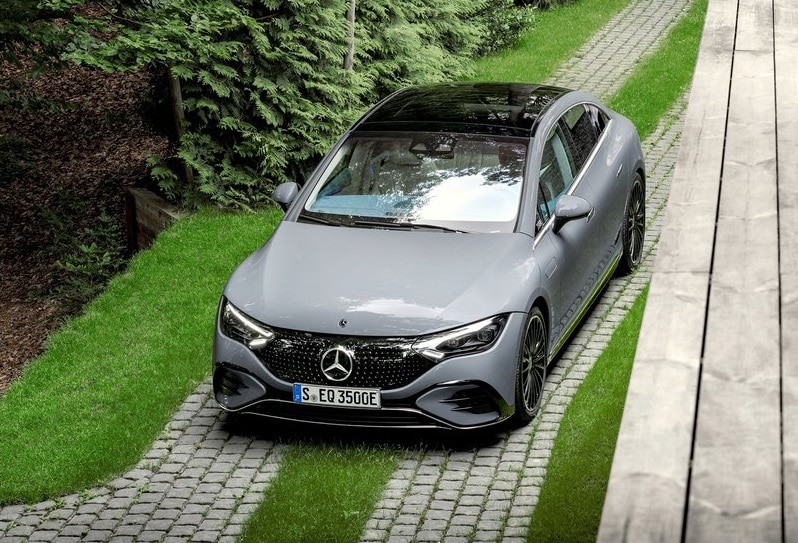 Gri Mercedes-Benz EQE sedanın taş döşeli yolda yüksek açıdan ön görünümü