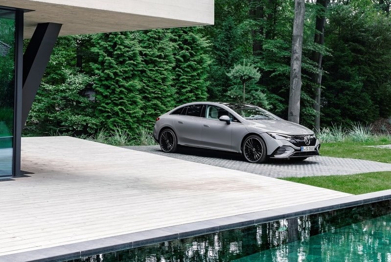 Gri Mercedes-Benz EQE sedanın havuz kenarında park edilmiş ön üç çeyrek görünümü