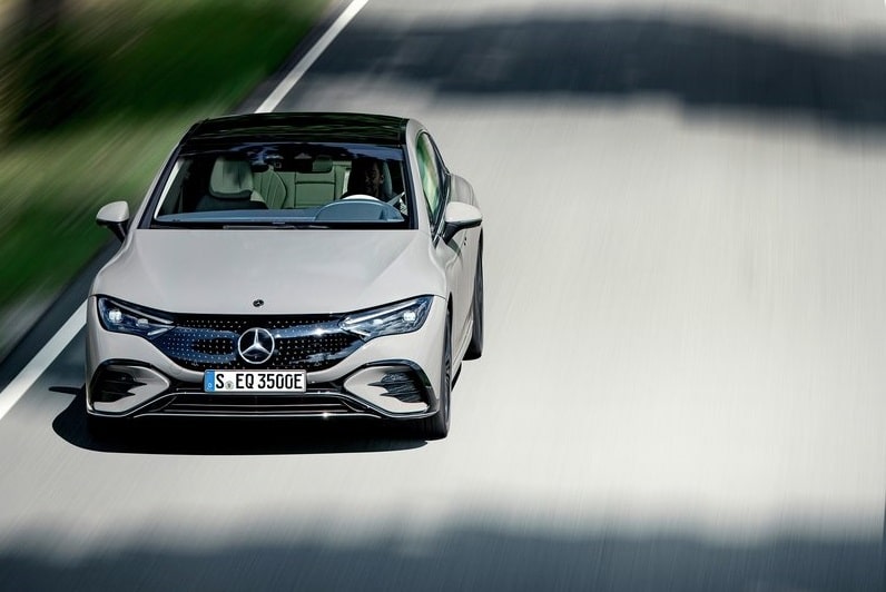 Beyaz Mercedes-Benz EQE sedanın yolda ilerlerken önden görünümü