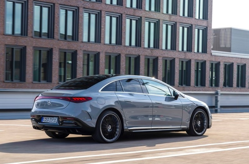 Gri Mercedes-Benz EQE sedanın şehir içinde hareket halindeki arka görünümü