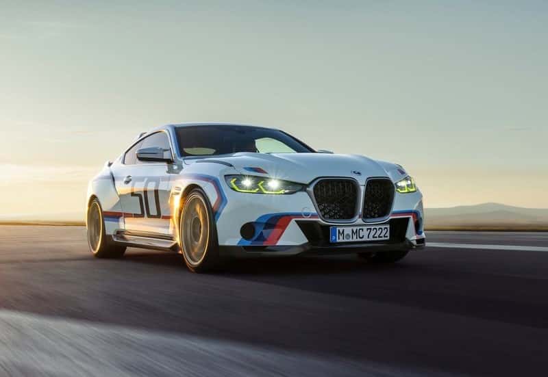 Beyaz BMW coupe yolda ön üç çeyrek açıdan hareket halinde