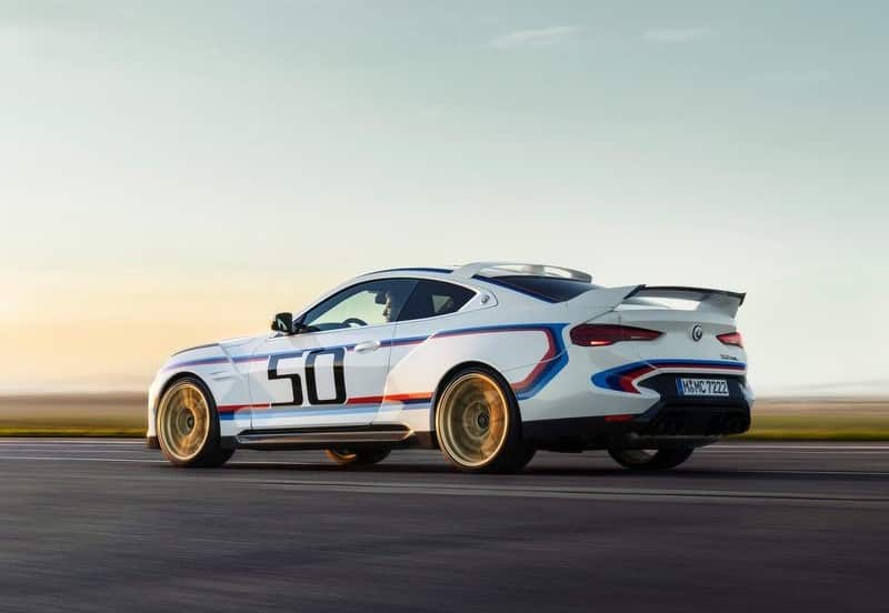 Beyaz BMW coupe yolda arka üç çeyrek açıdan hareket halinde